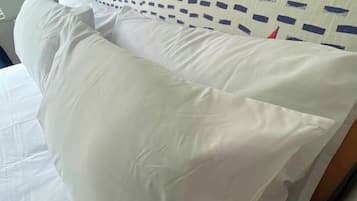 A bed with white bedding and a headboard with a geometric pattern.