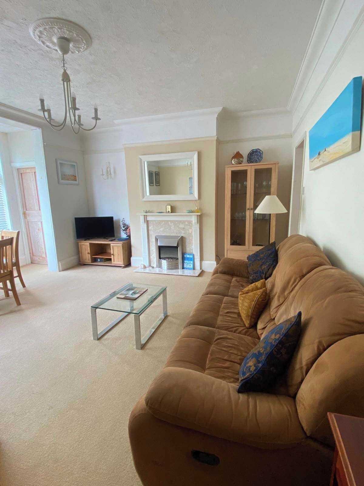 A living room with a sofa, a fireplace, a television, and a dining area.