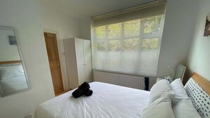 Una habitación de hotel con cama, armario, radiador y ventana con persianas.