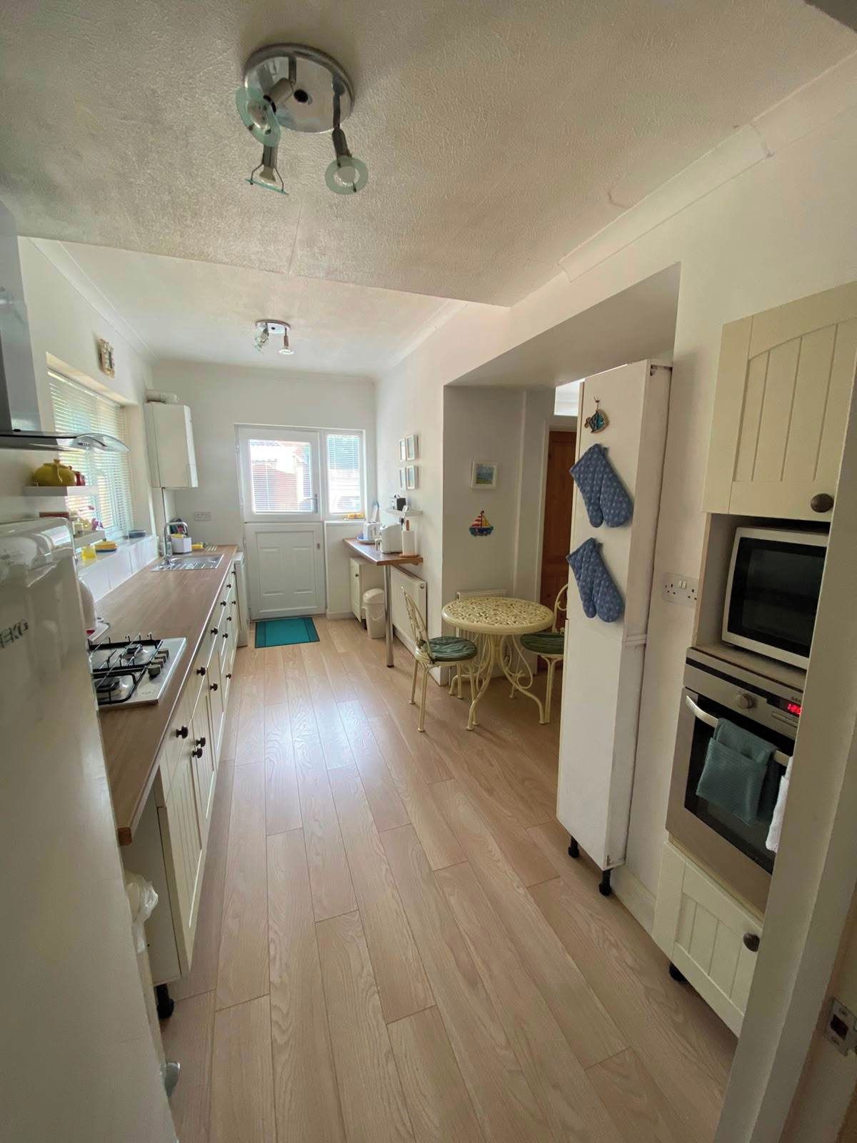 A kitchen with a gas stove, oven, and a dining area with a table and chairs.