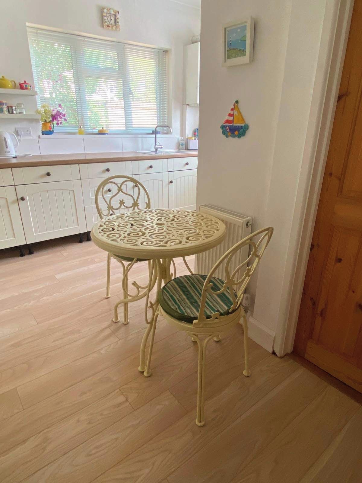 Un coin repas avec une table ronde et des chaises, une cuisine en arrière-plan et une porte en bois.