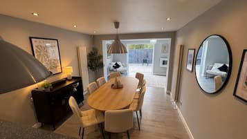 A modern dining area with a wooden table and chairs, a black console, and a large pendant light.