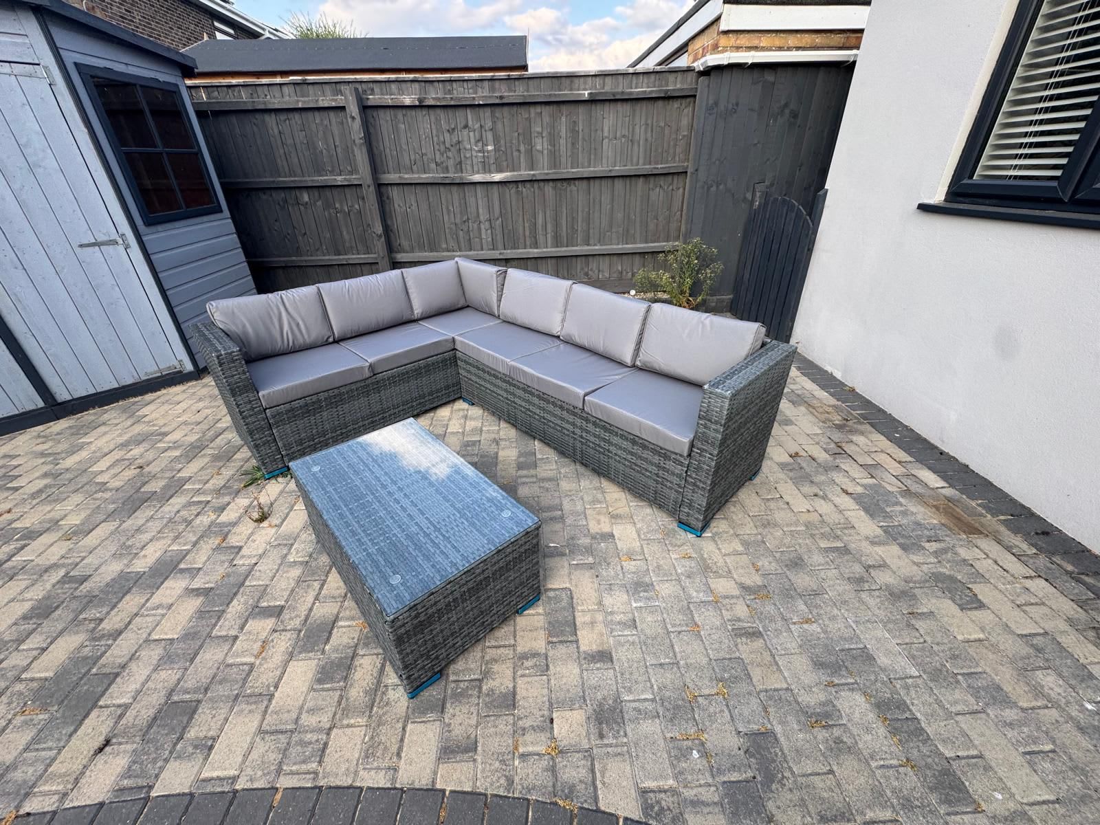 A sectional sofa with a matching ottoman in a paved outdoor area.