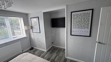 A bedroom with a bed, a TV, a framed artwork, and a radiator.