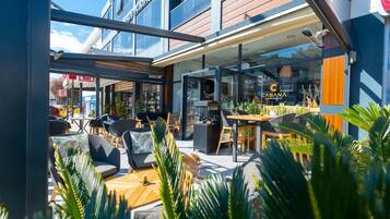 An outdoor seating area with tables and chairs, a dog, and a glass storefront with the name 'CABANA' visible.