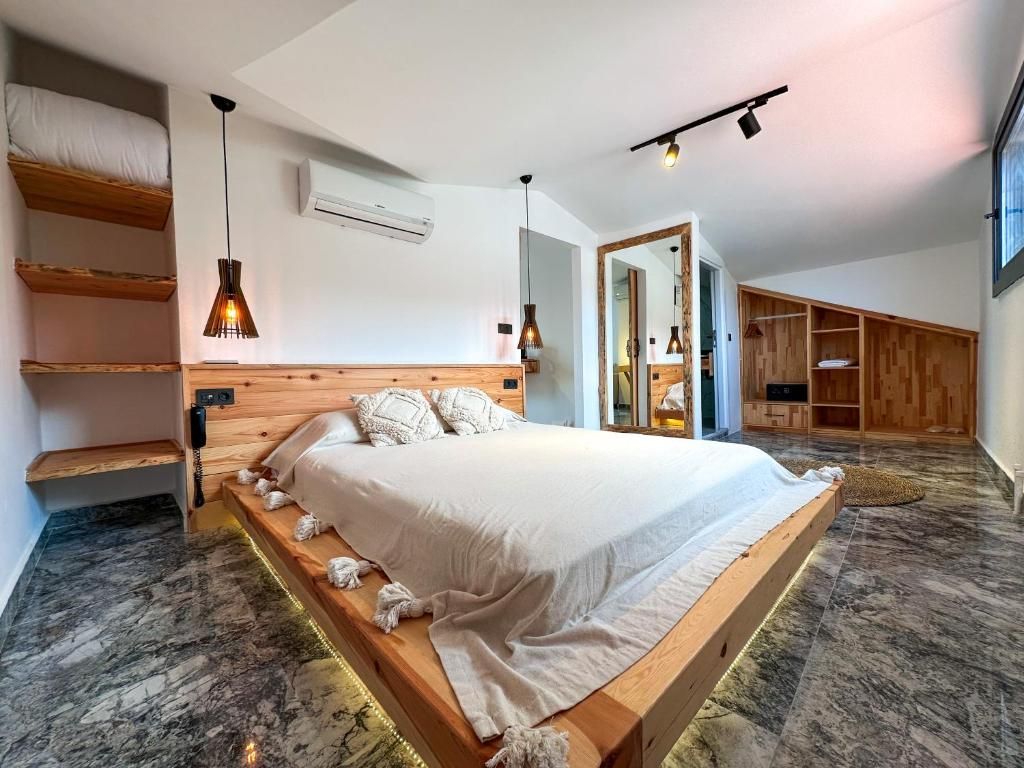 A modern bedroom with a large bed, wooden headboard, and built-in shelving.