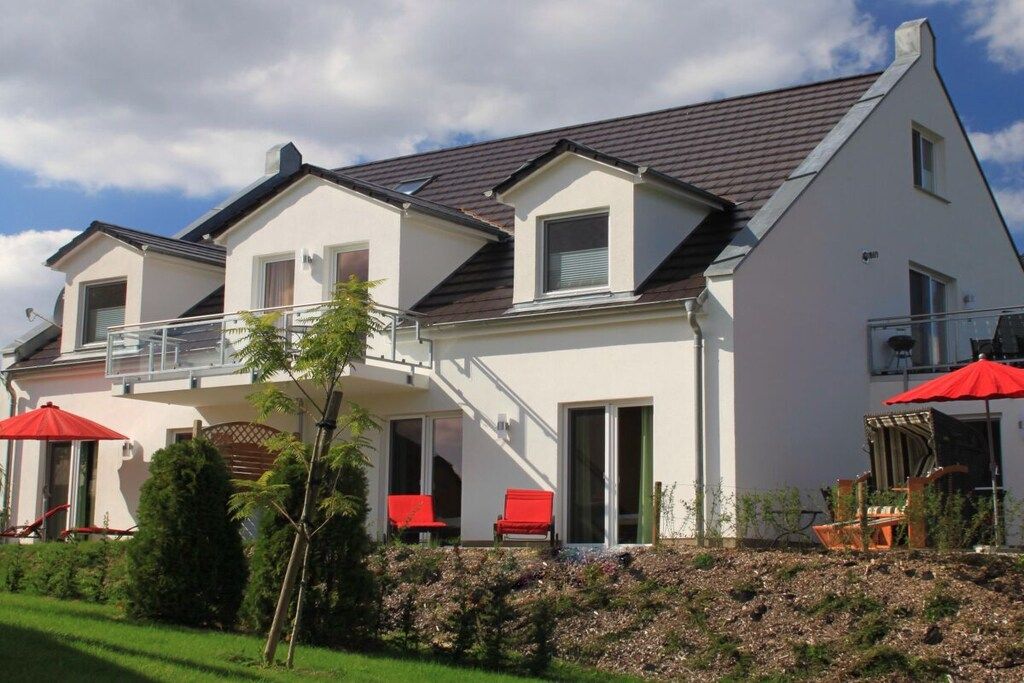 A two-story house with a balcony, a covered patio area, and a well-maintained garden.