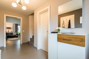 Ein modernes Interieur mit einem weißen Schrank, einem Spiegel und einer Treppe, die in einen anderen Raum führt.