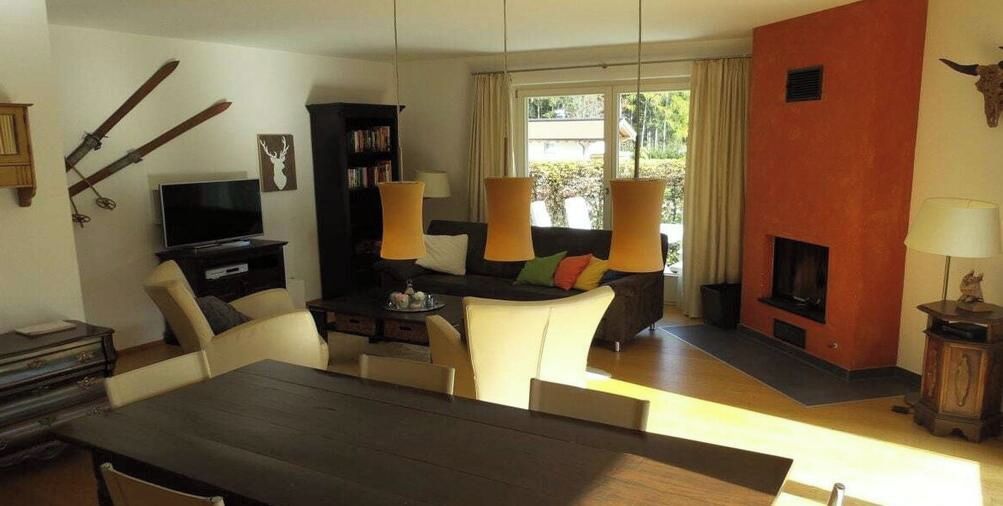 A living room with a fireplace, a television, and a dining area with a table and chairs.