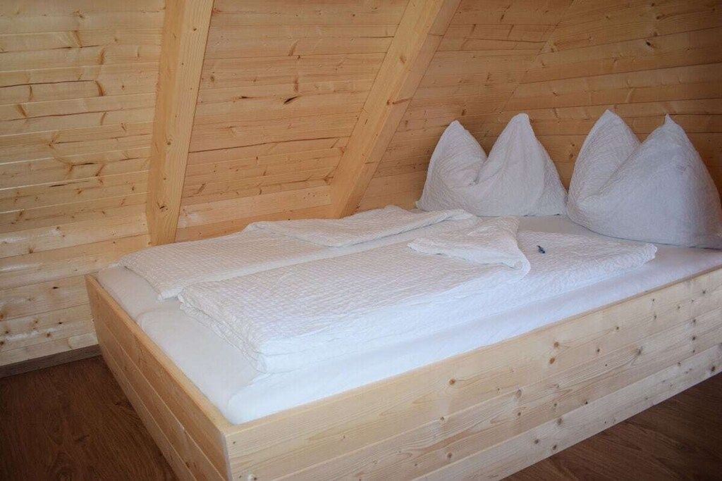 Un lit superposé en bois, avec une literie et des oreillers blancs, dans une chambre décorée dans le style d’un chalet.