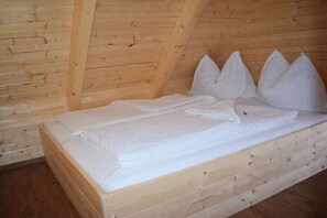 A wooden bunk bed with white bedding and pillows in a cabin-style room.
