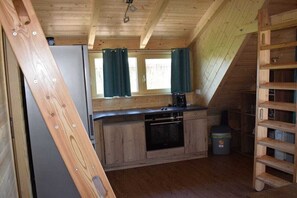 Une cuisine de taille réduite, dotée de meubles en bois, d’un four encastré et d’une fenêtre avec des rideaux.