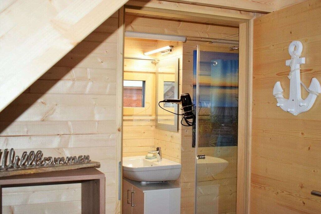 A wooden interior with a glass shower enclosure, a sink, and a cabinet.