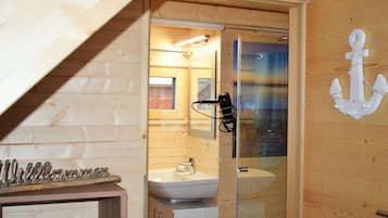 A wooden interior with a glass shower enclosure, a sink, and a cabinet.