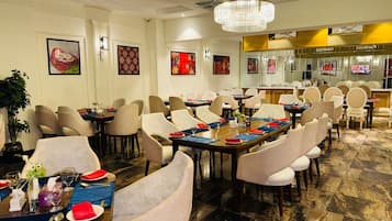 Un comedor de hotel con mesas redondas, sillas y una araña.
