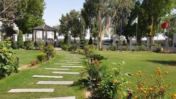 A garden pathway leading to a gazebo, surrounded by well-maintained grass and flowering plants.