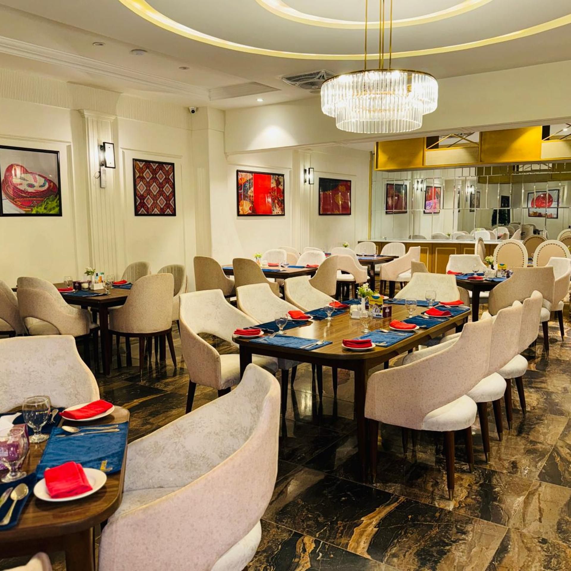 Uma sala de jantar de hotel com várias mesas, cadeiras e um candelabro.