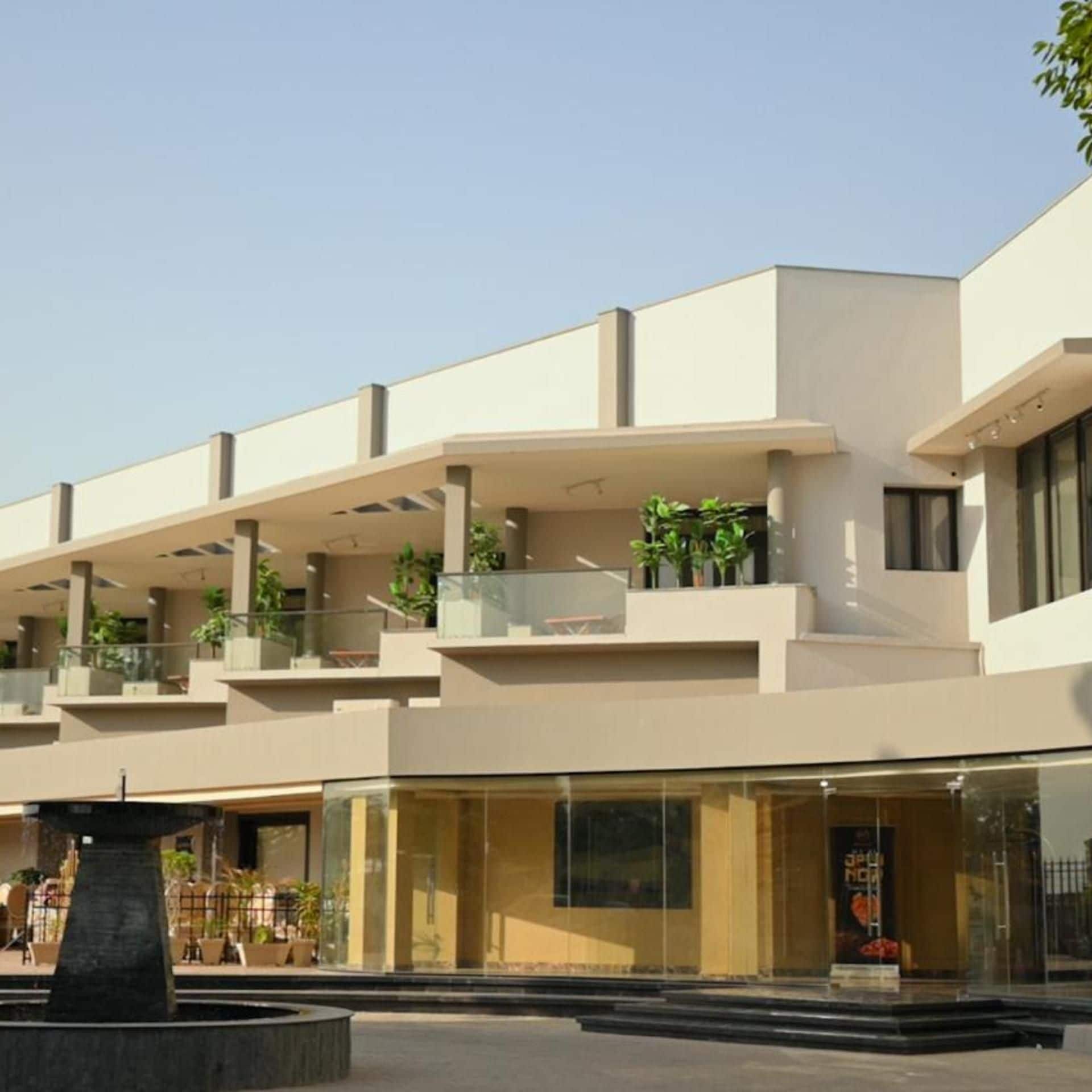 Un bâtiment moderne doté de nombreux balcons, de grandes fenêtres et d’une fontaine centrale.