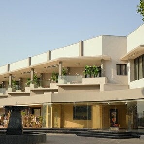 Un edificio moderno con varios balcones, ventanas amplias y una fuente central.