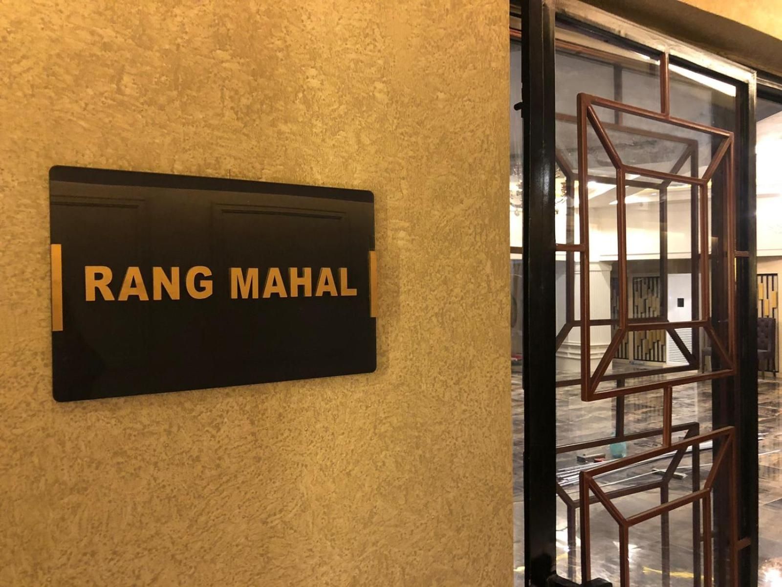 Una señal con el nombre 'RANG MAHAL' sobre una pared texturizada, indicando el nombre del hotel.