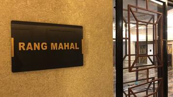 Una señal con el nombre 'RANG MAHAL' sobre una pared texturizada, indicando el nombre del hotel.