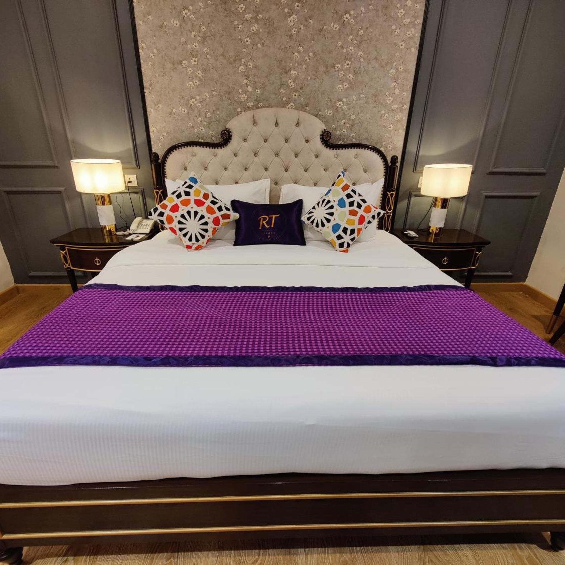 A hotel room with a large bed, two bedside tables with lamps, and a decorative headboard.