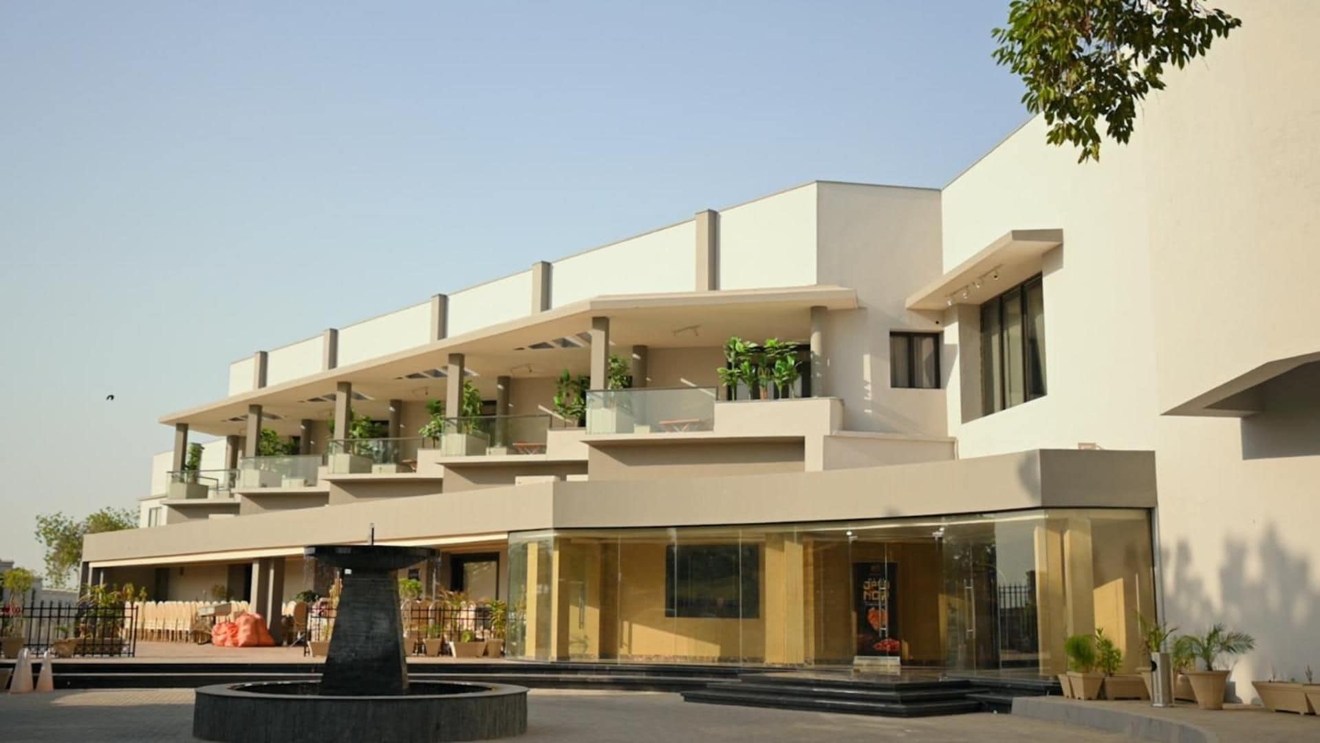 A modern building with multiple balconies, a central fountain, and a clear sky.