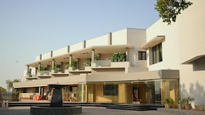 A modern building with multiple balconies, a central fountain, and a clear sky.