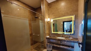 Een moderne badkamer met een douchecabine van glas, een marmeren aanrechtblad en een grote spiegel.