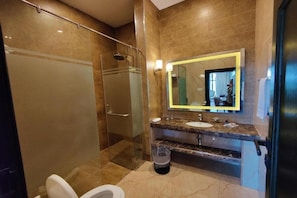 A modern bathroom with a glass-enclosed shower, a marble countertop, and a large mirror.