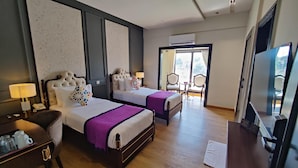 Een hotelkamer met twee bedden, een bureau met lamp, een stoel en een televisie.
