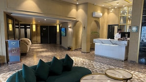 Een hotellobby met een receptiebalie, een bank en een vloer met een patroon.