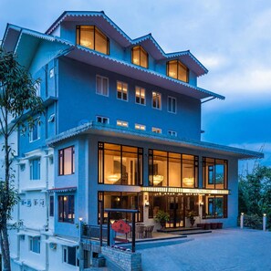 Un hôtel à plusieurs étages, doté d’une entrée imposante, de grandes fenêtres et d’une façade bien éclairée.