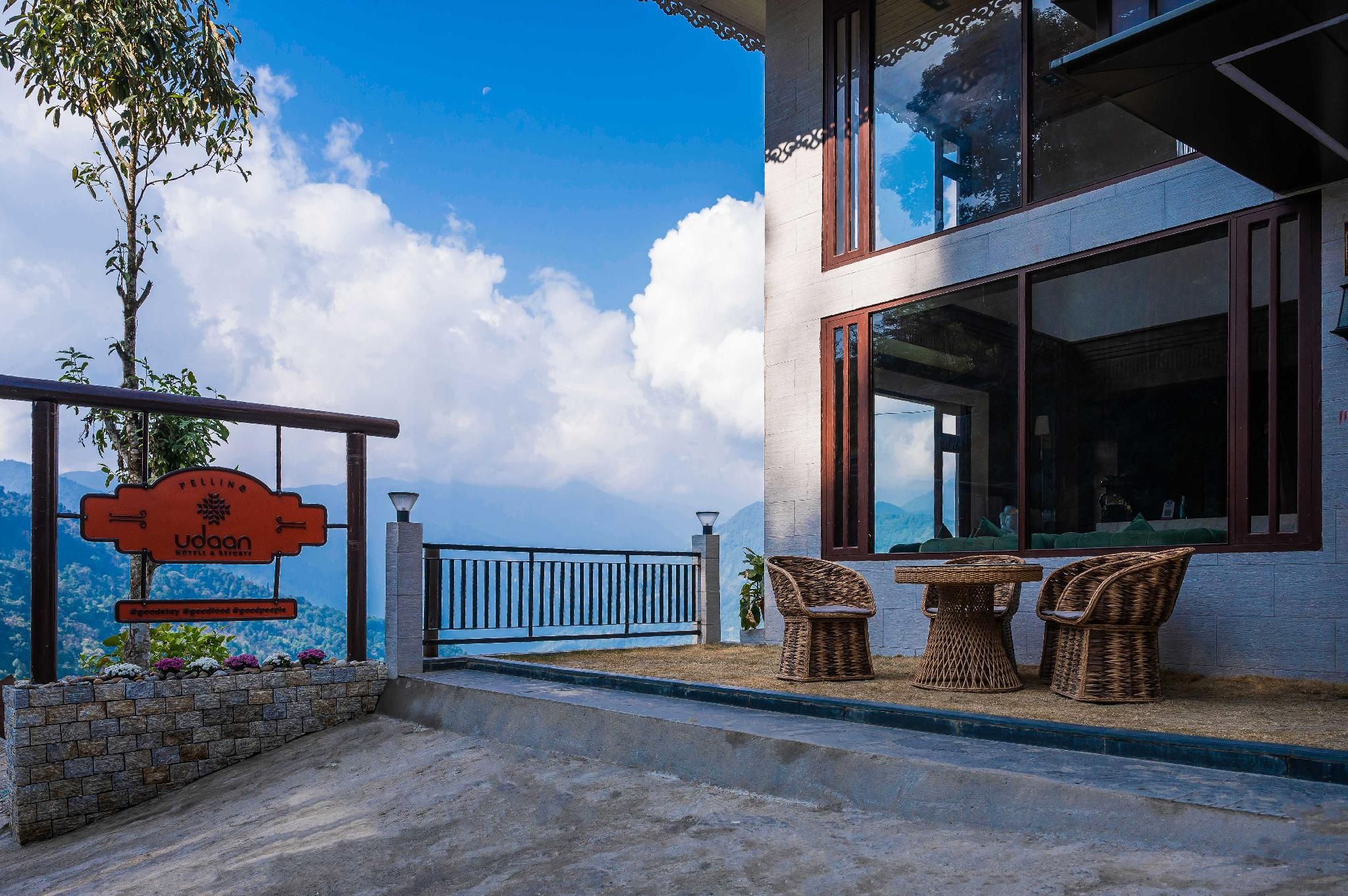 A hotel with a balcony, wicker furniture, and a mountain view.
