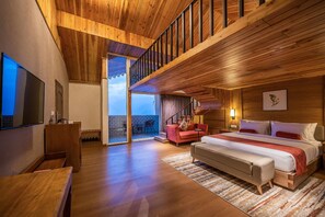 Une chambre spacieuse avec un grand lit, un coin salon et un balcon offrant une vue agréable.