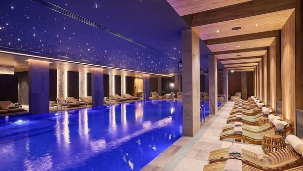 Un espace spa doté d’une piscine, de chaises longues et d’un plafond étoilé.