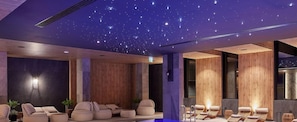 Una habitación con techo estrellado, paneles de madera y varias zonas de estar con cojines.