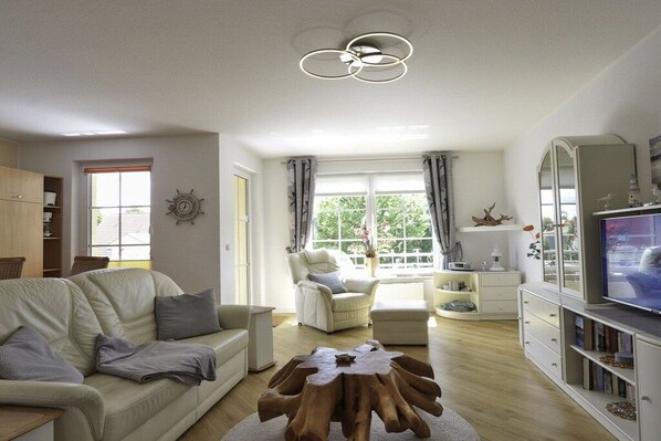 Un salon comprenant un canapé, un fauteuil, une table basse et un téléviseur.