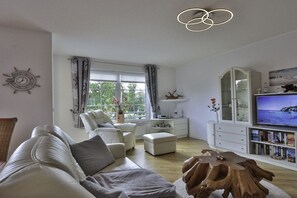 Ein Wohnzimmer mit einer Couch, einem Couchtisch, einem Fernseher und einer Bücherwand.