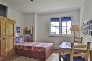 Ein Schlafzimmer mit einem Bett, einem Holzschrank, einem Tisch und einem Fenster.