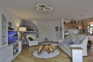 Un salon moderne avec un téléviseur, une table basse en bois et un canapé.