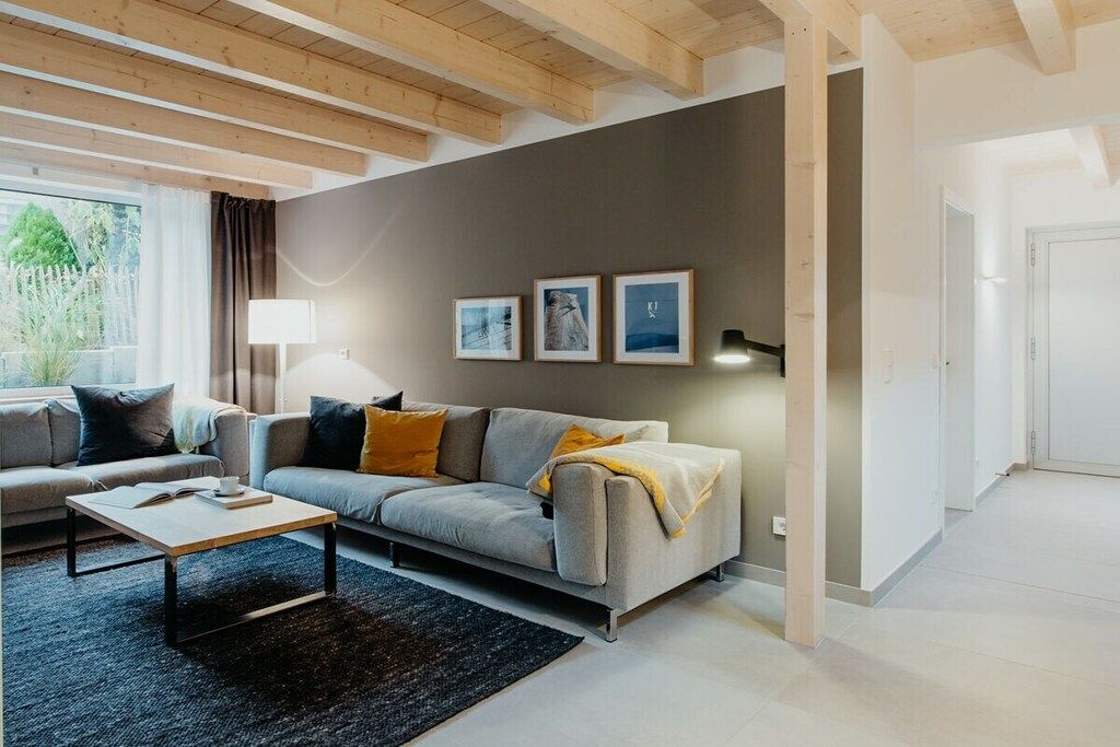 A modern living room with a sofa, coffee table, and a lamp. There are three framed pictures on the wall.