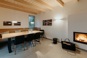 Ein modernes Interieur mit Holzboden, einem Esstisch mit Stühlen, einem Kamin und Wandbildern.