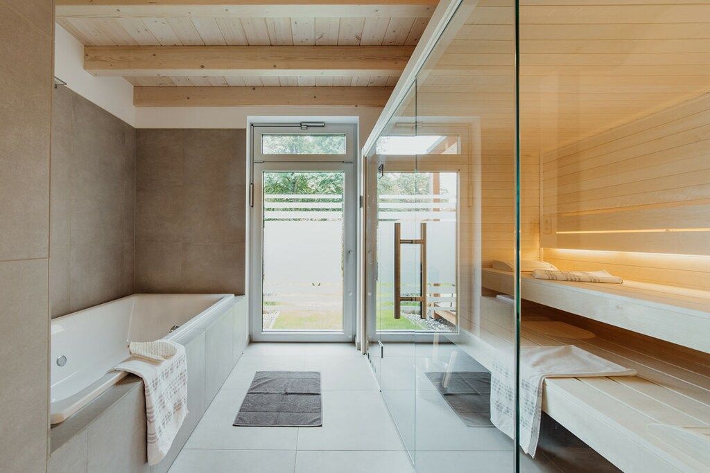 A modern bathroom with a bathtub, a glass shower enclosure, and a sauna area.
