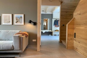 A modern interior with a sofa, wooden wall paneling, and a hallway leading to a bathroom. - Holiday home in Zinnowitz with sauna (Zinnowitz)