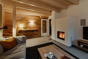 A modern living room with a fireplace, wooden ceiling, and a sofa. - Holiday home in Zinnowitz with sauna (Zinnowitz)