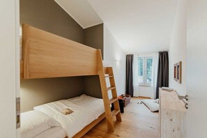 A room with a bunk bed, a wooden dresser, and a window with curtains. - Holiday home in Zinnowitz with sauna (Zinnowitz)