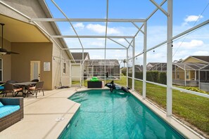 Ein Innenpool mit Glasveranda, umgeben von einer Terrasse mit Gartenmöbeln.