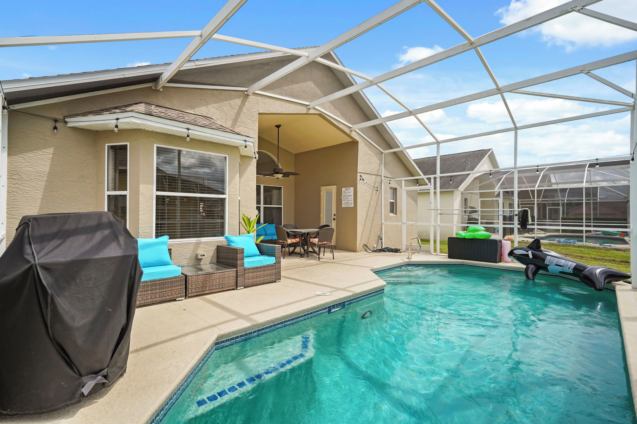 A covered outdoor area with a pool, seating, and a greenhouse structure.