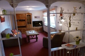 A living room with a television, wooden cabinets, a sofa, and a table. - Holiday home Elbe Sandstone Mountains (Königstein)